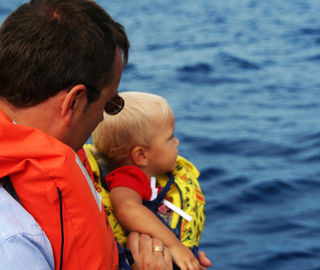 Dad and a baby whatching dolphins